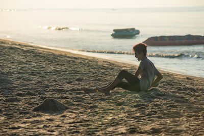 Side view of man sitting on beach