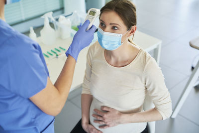 Doctor checking temperature of female patient in hospital