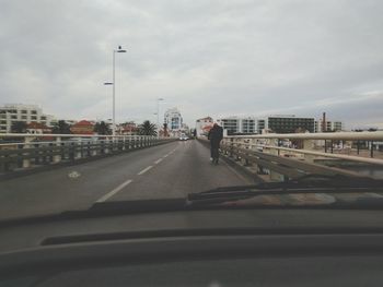 Man moving on road in city against sky