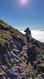 Rear view of man with arms outstretched against clear sky