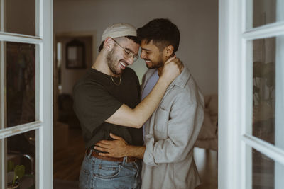 Loving gay couple standing with each other smiling at home