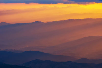 Scenic view of silhouette mountains against orange sky