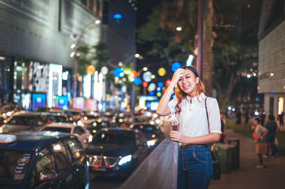 Portrait of young woman standing on city street at night