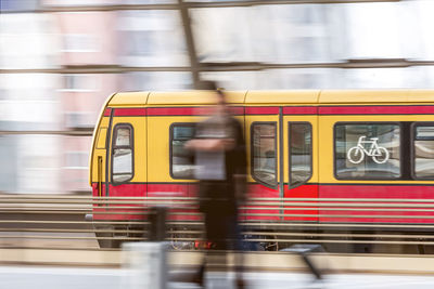 Blurred motion of person and train at railroad station platform