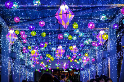 Group of people walking in illuminated street lights at night