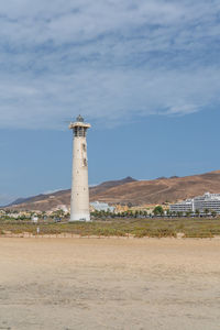 Lighthouse on street amidst buildings against sky