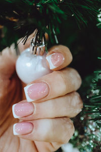 Female hand with french manicure holding a tinny toy silver christmas ball 