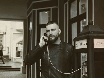 Portrait of mid adult man calling through telephone booth