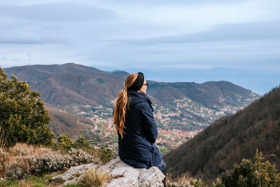 Rear view of woman standing on mountain against sky