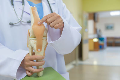 Midsection of doctor holding artificial joint