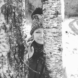 Portrait of smiling woman standing by tree in forest
