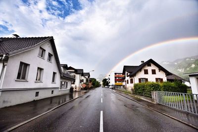 Road amidst houses against sky