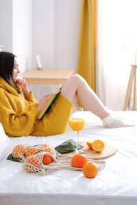 Young woman sitting on bed at home