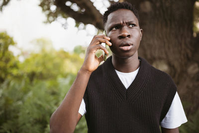 Young african man talking on phone shoked, stressed, unsatisfied