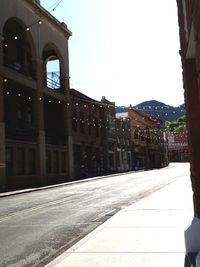 Empty road by buildings against clear sky