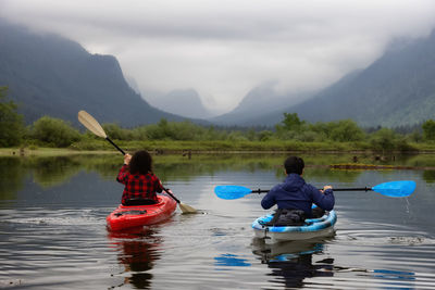 Rear view of men on boat in lake