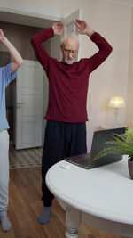 Senior man doing home workout through laptop