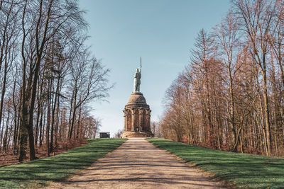 Footpath amidst trees and building against sky