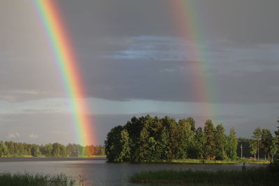 Scenic view of lake against rainbow in sky