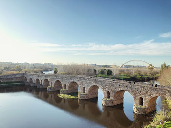 Arch bridge over river against sky