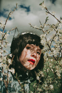 Portrait of young woman looking at tree