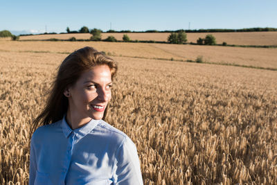 Beautiful woman looking away against wheat field