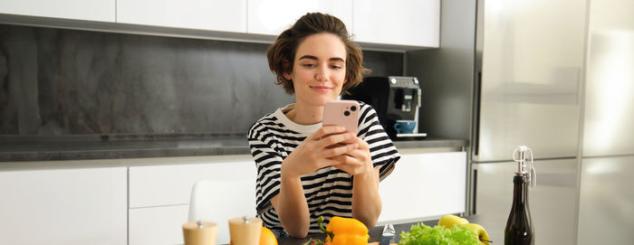 Portrait of smiling young woman drinking water at home