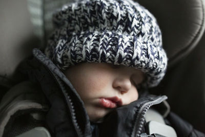 Close-up of toddler boy asleep in carseat while traveling in car