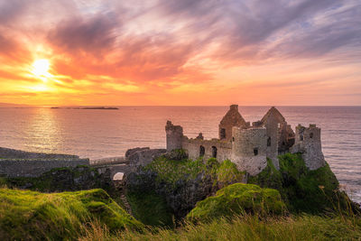 Sunset at ruins of dunluce castle located on the edge of cliff, bushmills, northern ireland