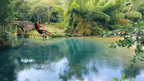 Man swinging above calm river