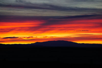Scenic view of silhouette mountains against orange sky