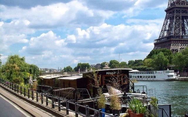 architecture, built structure, water, sky, cloud - sky, building exterior, cloudy, transportation, river, tree, nautical vessel, cloud, bridge - man made structure, day, connection, mode of transport, railing, outdoors, city, boat