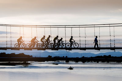 Man with cyclists on footbridge over river