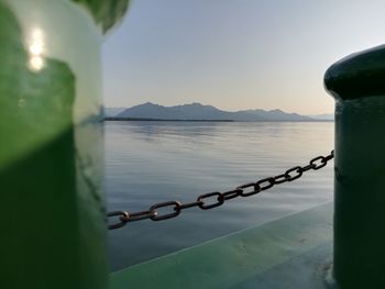 Close-up of chain against sea against sky during sunset