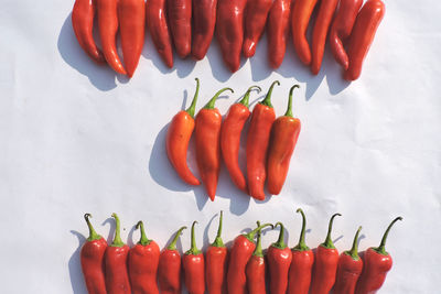 High angle view of red chili peppers against white background