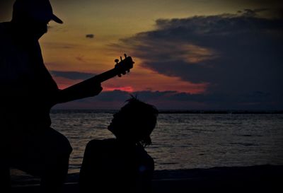 Silhouette men on beach against sky during sunset