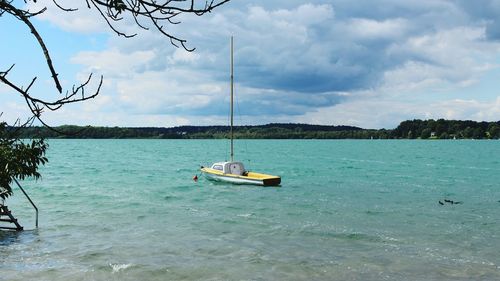 Boats in sea against cloudy sky