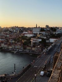 High angle view of buildings by river against sky during sunset