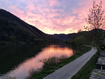 Scenic view of lake by mountains against sky at sunset