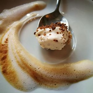 High angle view of cream in spoon and coffee froth