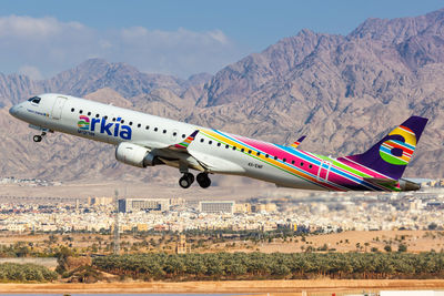 Airplane flying over mountains against sky