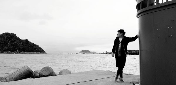 Full length of man standing on pier in sea against sky