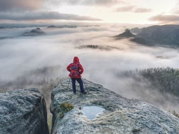 Rear view of man standing on rock against sky