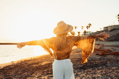 Rear view of woman standing at beach against clear sky