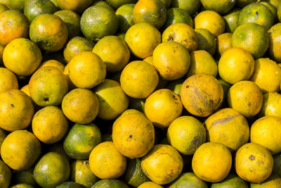 Background of oranges pile on stall in market in sunlight.