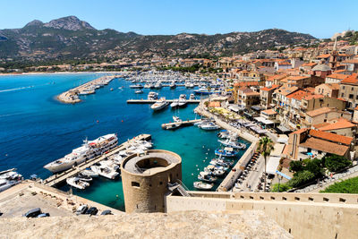 High angle view of townscape by sea against blue sky