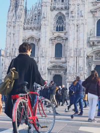 Rear view of people walking on street amidst buildings in city