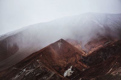 Smoke emitting from mountain against sky