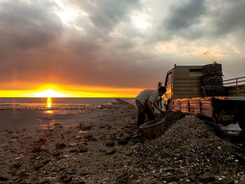 Man on beach against sky during sunset