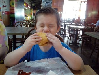 Full length of a girl eating food at restaurant